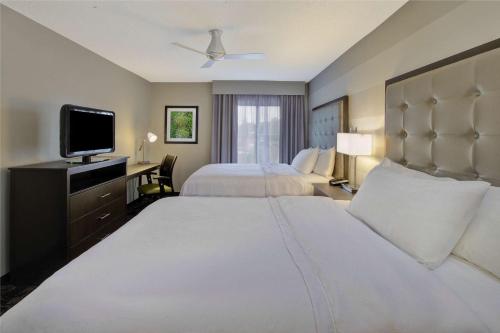 a hotel room with two beds and a flat screen tv at Homewood Suites by Hilton Dayton South in Miamisburg