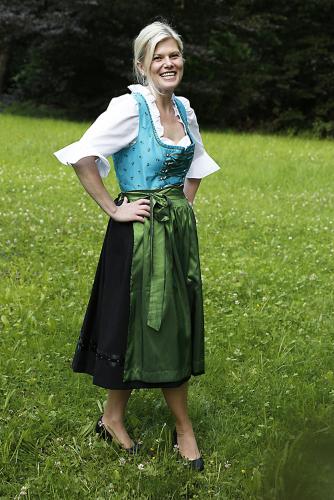 a woman in a green dress standing in a field at Gästehaus-Pension Bendler in Kirchdorf in Tirol