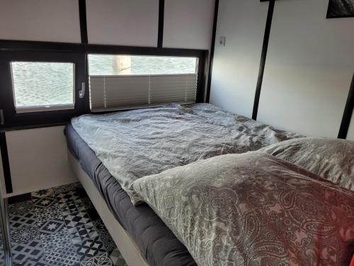a small bed in a room with two windows at Houseboat of Grimm in Fehmarn