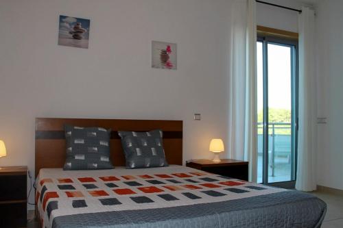 ein Schlafzimmer mit einem Bett mit zwei Lampen und einem Fenster in der Unterkunft Varandas do Mar Apartamento T2R frente mar Olhos de gua Albufeira in Olhos de Água