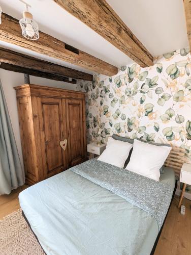 1 dormitorio con 1 cama con pared de flores en Le nid d'hirondelle, en Gertwiller