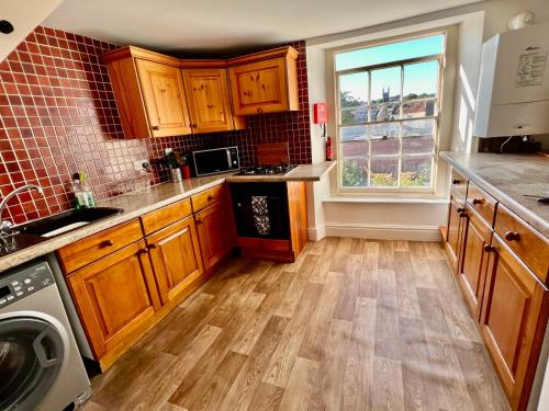 a kitchen with wooden cabinets and a large window at 3 bed penthouse flat with conservatory & roof terrace - city views in Bristol