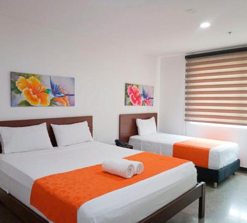 a bedroom with two beds with orange and white at HOTEL RIVERA CENTRAL in Bucaramanga