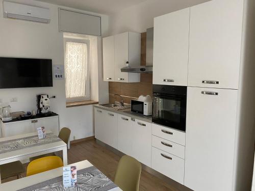 une cuisine avec des placards blancs, une table et une salle à manger dans l'établissement Villa Manto Bed and Breakfast - Torre Annunziata Pompei, à Torre Annunziata