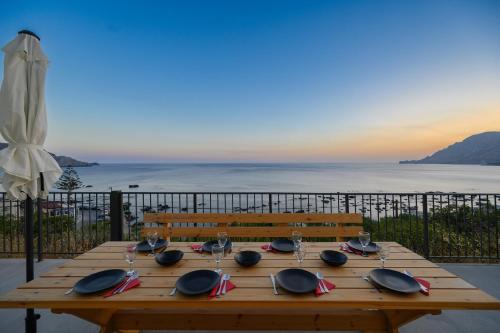 a wooden table with glasses and plates on top of it at Luz Villa next to the beach in Plakias