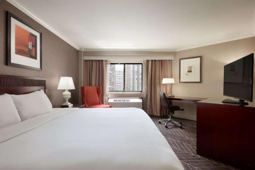 a hotel room with a bed and a desk and a television at Hilton Arlington in Arlington