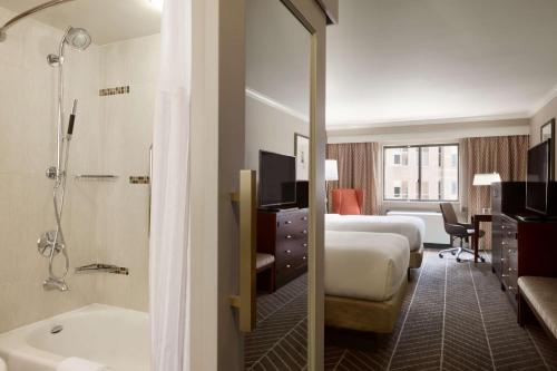 a hotel room with two beds and a bath tub at Hilton Arlington in Arlington