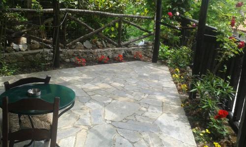 a stone patio with a table and chairs and flowers at Traditional Guesthouse Archontoula in Palaios Panteleimon