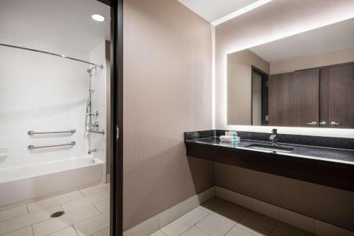 uma casa de banho com um lavatório, uma banheira e um espelho. em Homewood Suites- Denver Downtown Convention Center em Denver