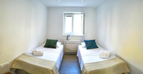 zwei Betten in einem kleinen Zimmer mit Fenster in der Unterkunft Rose - Heart of Zadar in Zadar