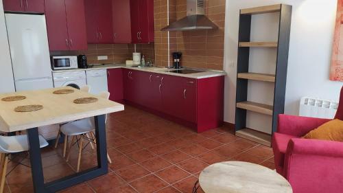 cocina con armarios rojos, mesa y encimera en Apartamento LA CORREDERA, en Arenas de San Pedro