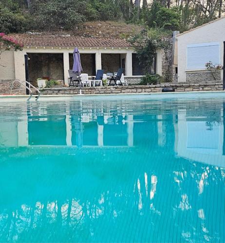 uma grande piscina de água azul em frente a uma casa em Hôtel Le Robinson em Beaucaire
