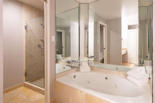 a white bathroom with a tub and a shower at Hilton Dallas Lincoln Centre in Dallas