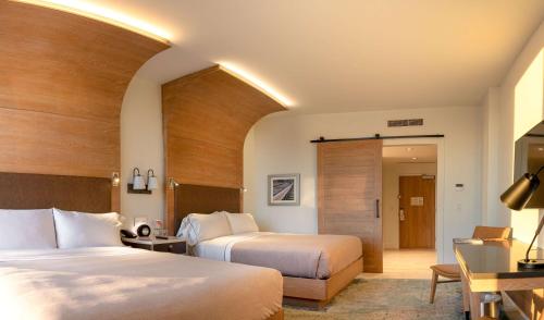 a hotel room with two beds and a desk at Canopy By Hilton Dallas Uptown in Dallas