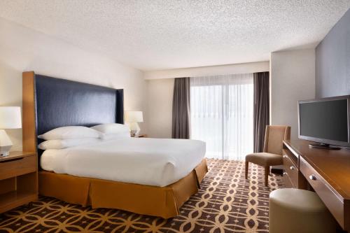 a hotel room with a bed and a flat screen tv at Embassy Suites Dallas - DFW International Airport South in Irving