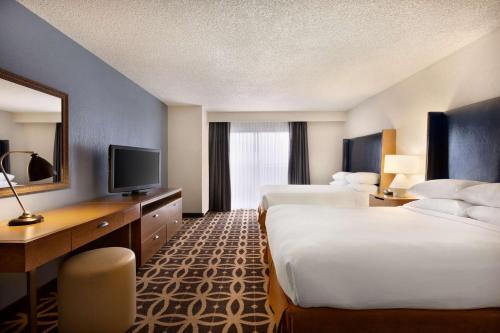 a hotel room with two beds and a television at Embassy Suites Dallas - DFW International Airport South in Irving