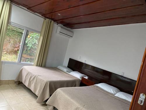 1 dormitorio con 2 camas y ventana en Hotel La Colonia, en Retalhuleu