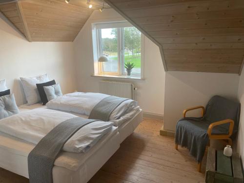 a bedroom with a large bed and a chair at Thyholm B&B in Thyholm