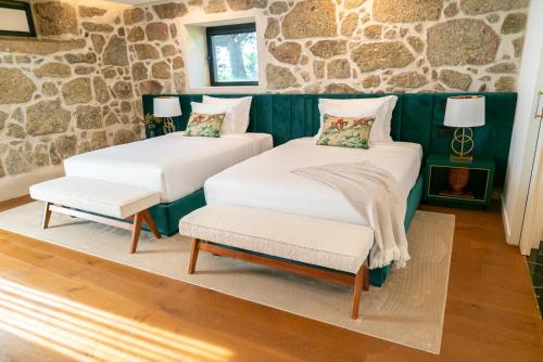 two beds in a room with a stone wall at Quinta de Silvalde in Santo Tirso