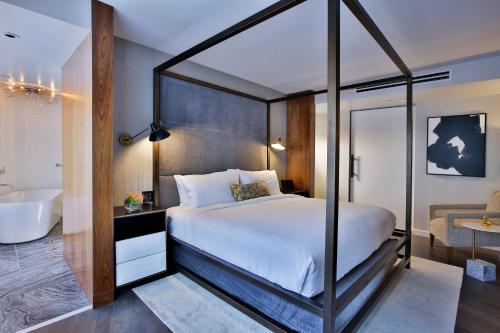a bedroom with a canopy bed and a bathroom at The Statler Dallas, Curio Collection By Hilton in Dallas