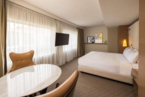 a hotel room with a bed and a table at The Statler Dallas, Curio Collection By Hilton in Dallas