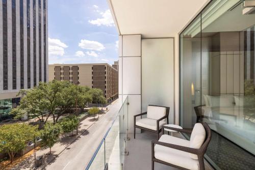 a balcony with two chairs and a view of a city at The Statler Dallas, Curio Collection By Hilton in Dallas