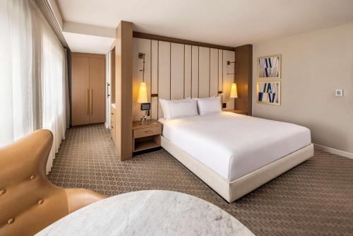 a bedroom with a large white bed and a chair at The Statler Dallas, Curio Collection By Hilton in Dallas