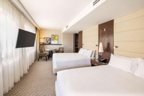 a hotel room with two beds and a television at The Statler Dallas, Curio Collection By Hilton in Dallas