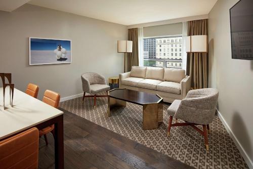 a living room with a couch and a table at The Statler Dallas, Curio Collection By Hilton in Dallas