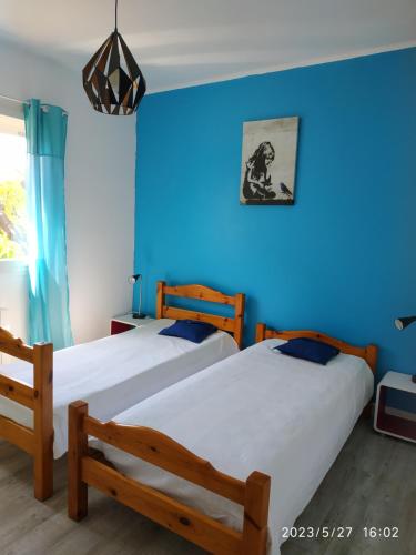 - 2 lits dans une chambre avec un mur bleu dans l'établissement Ondine Vacances, à Six-Fours-les-Plages