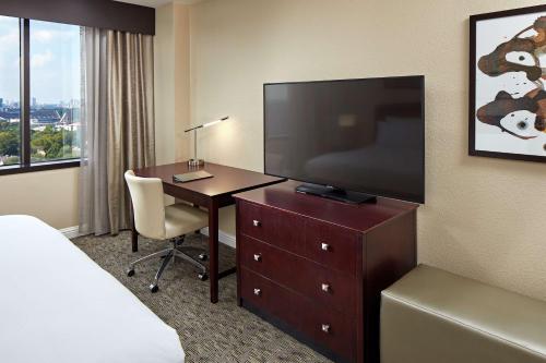 a hotel room with a desk and a flat screen tv at Hilton Houston Plaza/Medical Center in Houston