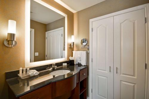 La salle de bains est pourvue d'un lavabo et d'un grand miroir. dans l'établissement Homewood Suites by Hilton Wilmington/Mayfaire, NC, à Wilmington