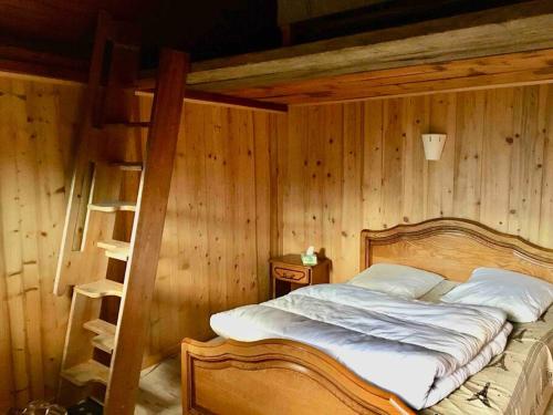 een slaapkamer met een bed met een houten muur bij Chalet accueillant pour des vacances reposantes in Jarrier