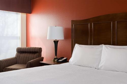 a bedroom with a bed and a chair and a lamp at Hampton Inn Lubbock in Lubbock