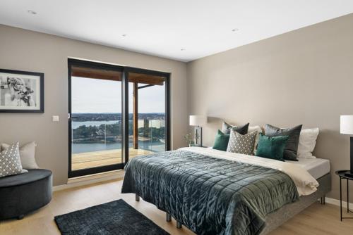 a bedroom with a large bed and a large window at Moderne nydelig villa med Panorama Utsikt in Sandefjord