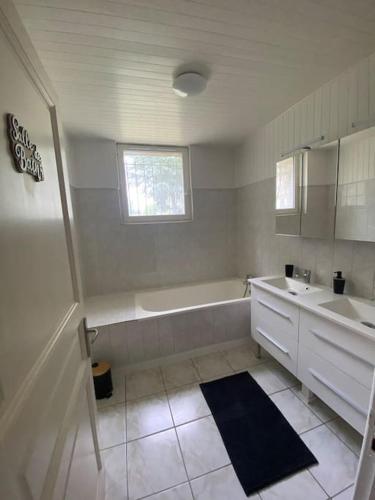 une salle de bain blanche avec une baignoire et un lavabo dans l'établissement Gîtes de Lartigue, à Anthé