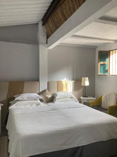 a bedroom with a large white bed with two chairs at Yoga Farm in Tavira