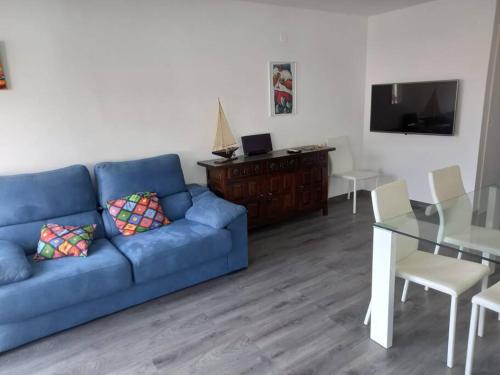 een woonkamer met een blauwe bank en een tafel bij Cuana Precioso apartamento 2 minutos playa, parking gratuito, Roses centro in Roses