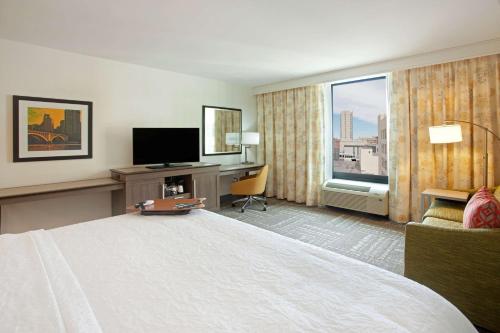 a hotel room with a large bed and a television at Hampton Inn & Suites - Minneapolis/Downtown in Minneapolis