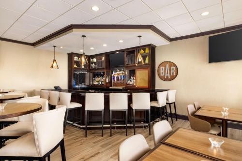 a bar in a restaurant with white chairs and tables at DoubleTree by Hilton New Orleans Airport in Kenner