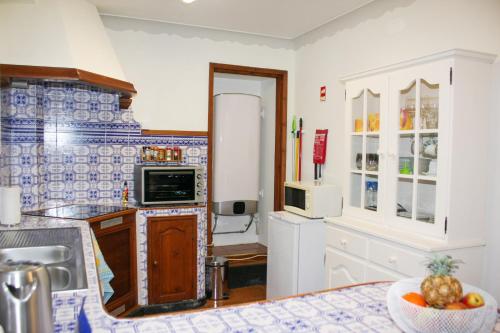 a kitchen with white cabinets and a bowl of fruit on the counter at Casa do Largo - Açores in Ponta Delgada