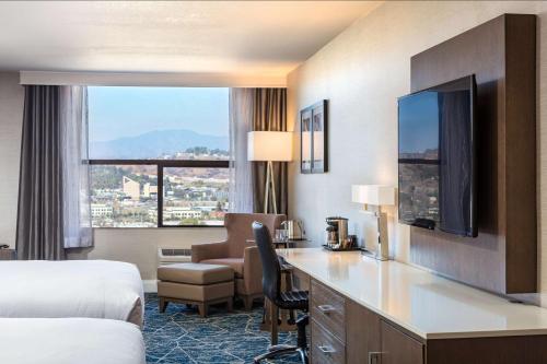 a hotel room with a bed and a desk with a desk at Doubletree By Hilton Pomona in Pomona