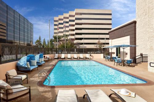 uma piscina com espreguiçadeiras e um edifício em Hilton Pasadena em Pasadena