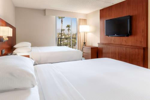 a hotel room with two beds and a flat screen tv at Hilton Pasadena in Pasadena