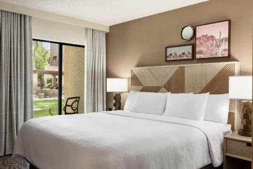 Embassy Suites by Hilton Phoenix Tempe في تيمبي: غرفة نوم بسرير كبير ونافذة كبيرة