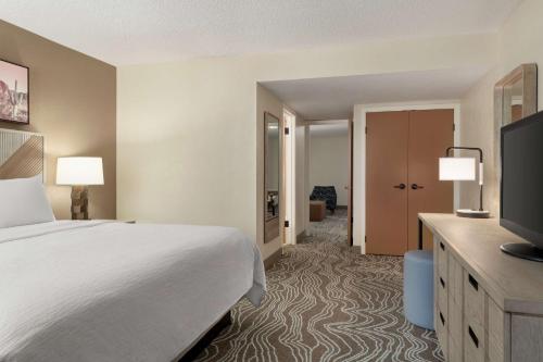 a hotel room with a bed and a flat screen tv at Embassy Suites by Hilton Phoenix Tempe in Tempe