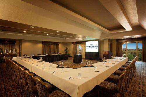 a large meeting room with a long table in front of a screen at Hilton Phoenix Tapatio Cliffs Resort in Phoenix