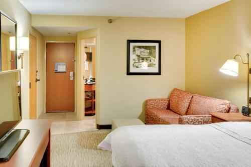 um quarto de hotel com uma cama e uma cadeira em Hampton Inn Pittsburgh/Airport em Moon Township