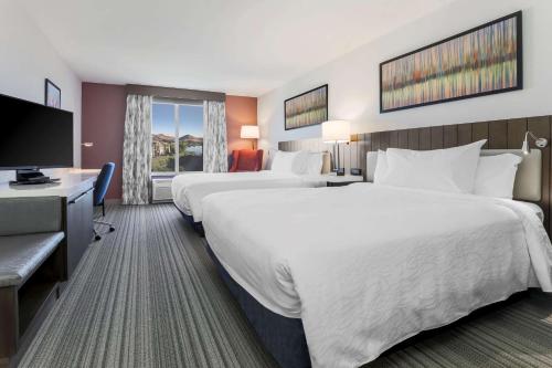 a hotel room with two beds and a flat screen tv at Hilton Garden Inn Reno in Reno