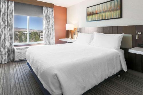 a hotel room with a large bed and a window at Hilton Garden Inn Reno in Reno